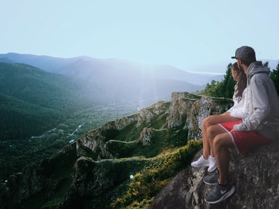 一对夫妇坐在悬崖边看山